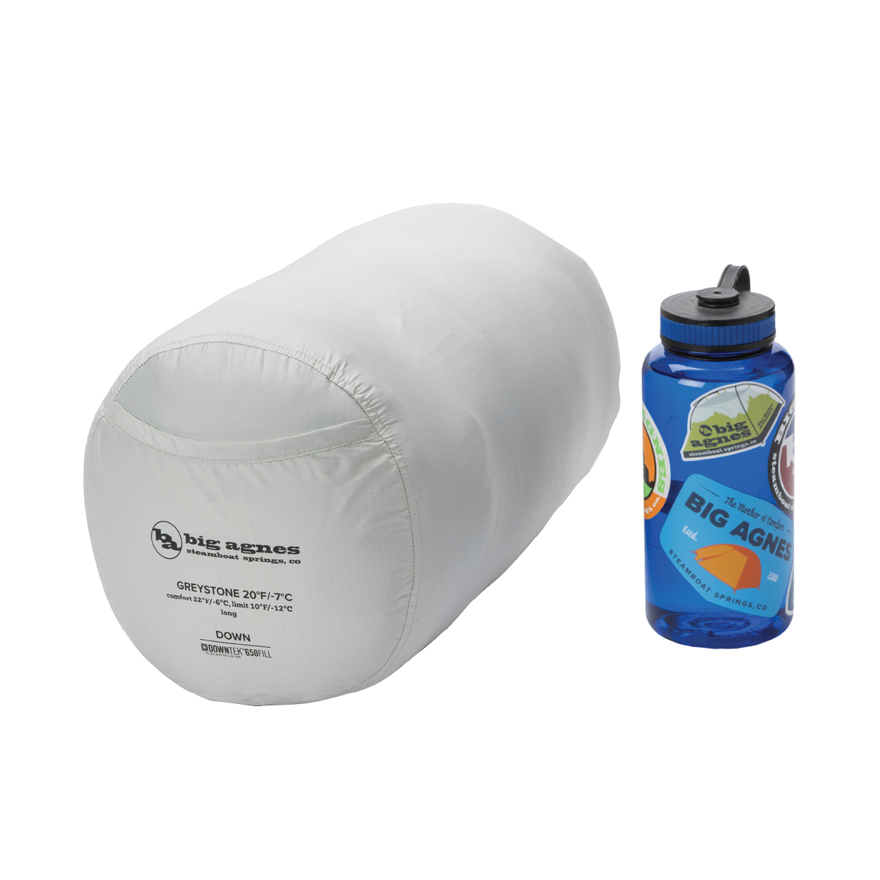 The Big Agnes Greystone 20° sleeping bag sits beside a blue, sticker-covered Nalgene, highlighting its compact size—ideal for backpacking trips.