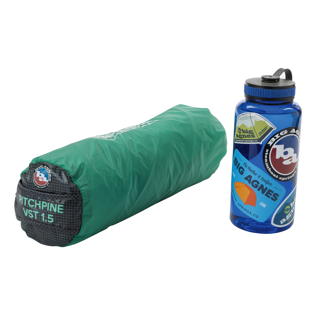 A rolled-up green Big Agnes Pitchpine VST 1.5 ultralight shelter sits next to a blue water bottle decorated with Big Agnes stickers.