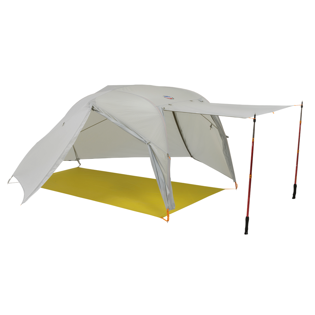 The Big Agnes Returns Salt Creek 2, a light gray backpacking tent, is shown with one side propped open by trekking poles for an awning and panoramic views, set up on a bright yellow groundsheet.