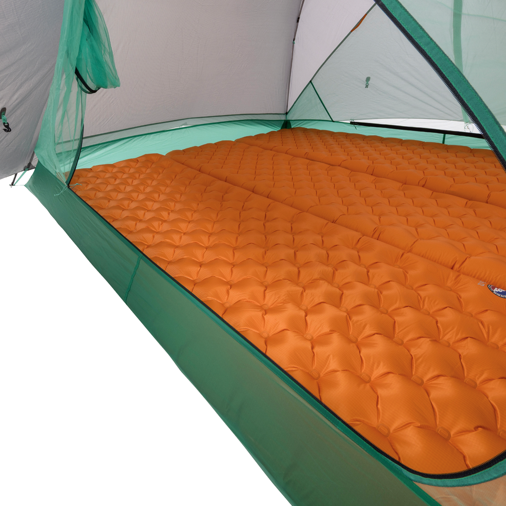 Two orange inflatable sleeping pads are laid out side by side inside a Big Agnes Sarvis VST 3 tent, covering the floor. Mesh sides and poles peek through, highlighting a cozy setup within this ultralight shelter.