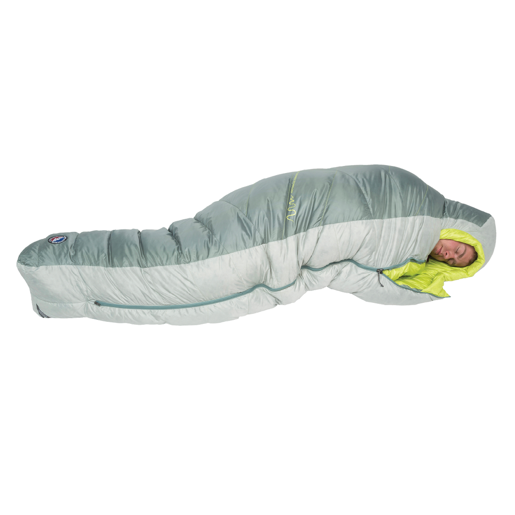 A person is sleeping inside the Big Agnes Sidewinder 0˚, a light gray and lime green mummy-style side sleeper sleeping bag with body-mapped insulation, fully zipped and snug around them, as they rest on a white background.
