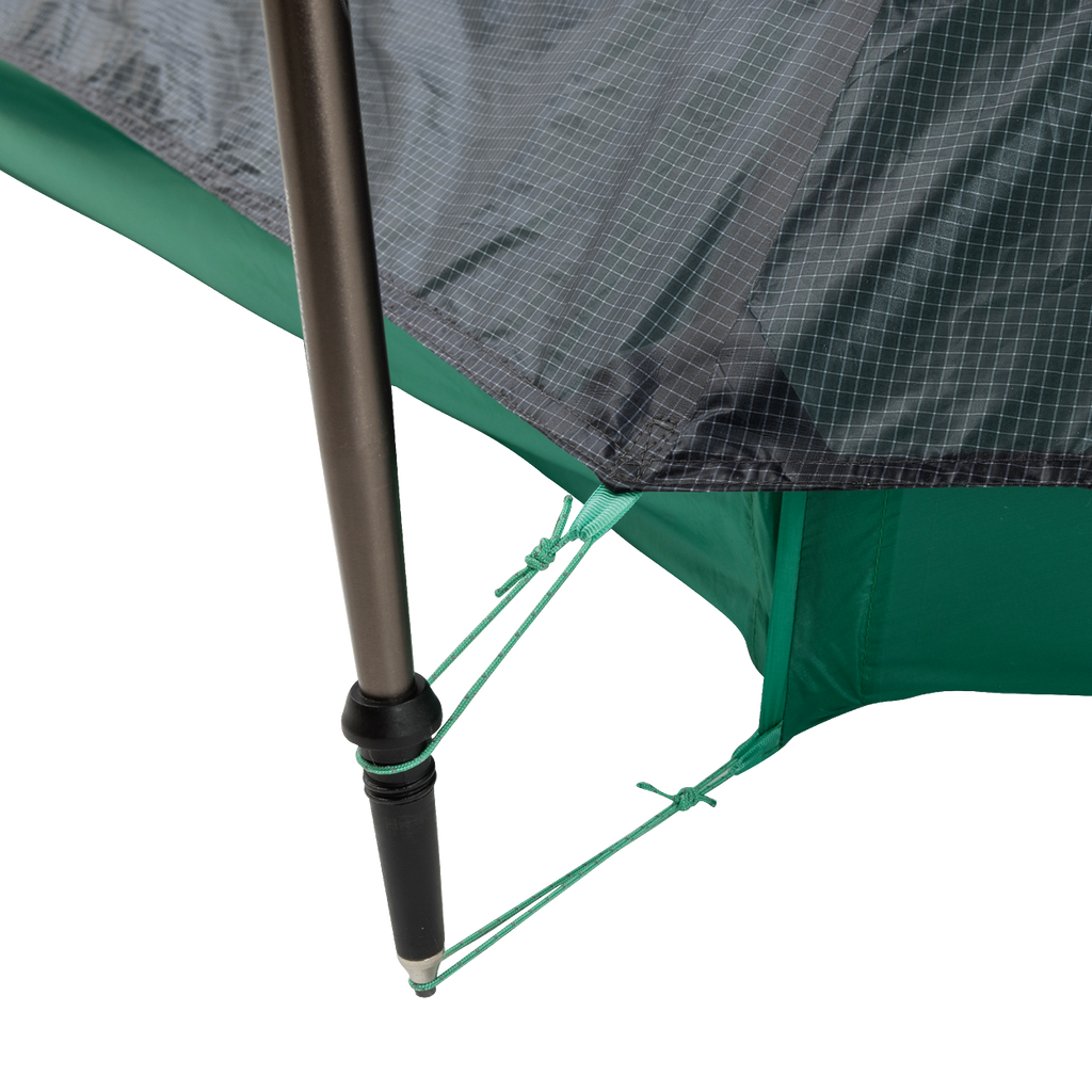 Close-up of a String Ridge VST 1.5 tent corner by Big Agnes Returns, showing a black pole secured with green guy lines on reinforced, grid-patterned green and gray fabric—highlighting this ultralight shelter’s durability and detailed design.