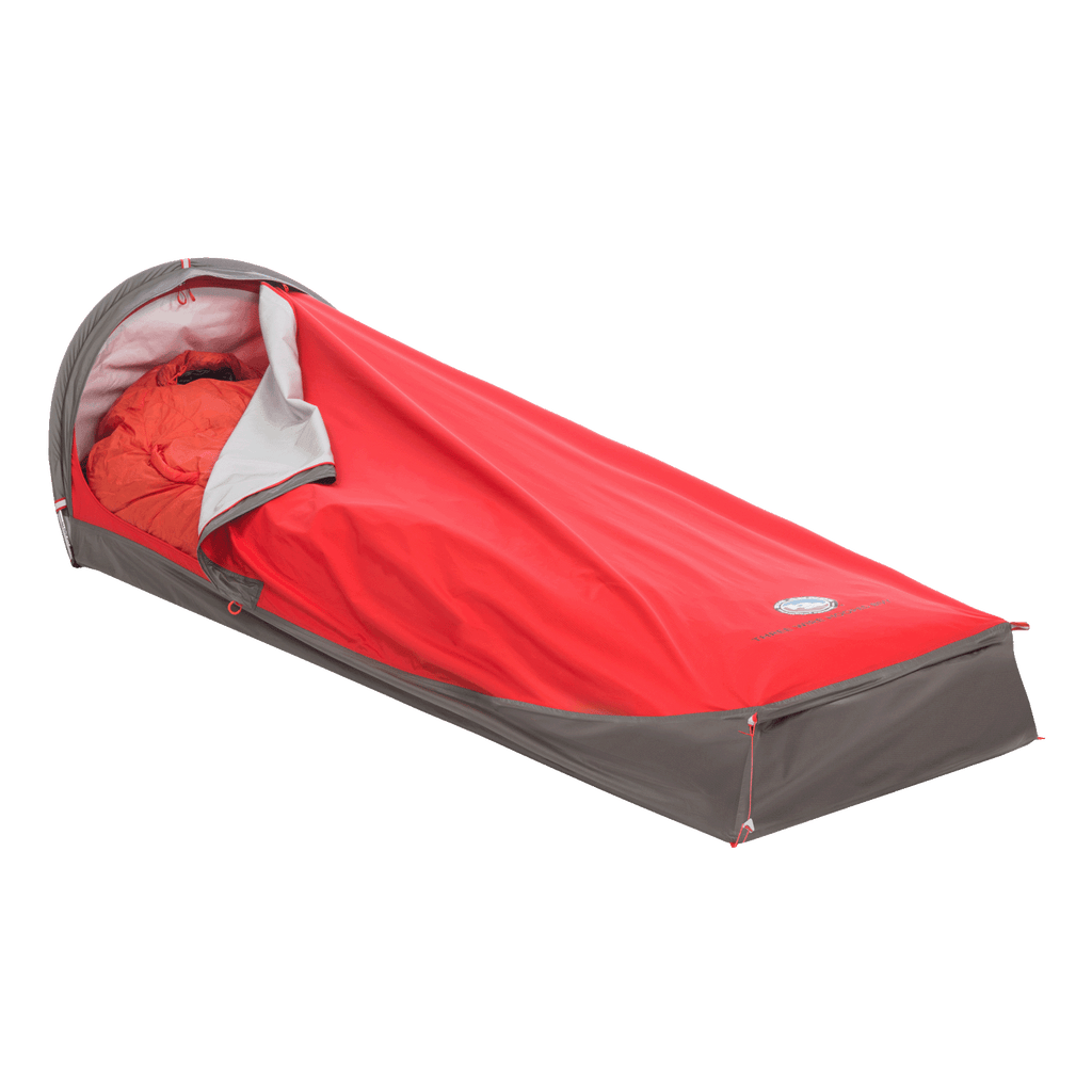 The Big Agnes Returns Three Wire Hooped Bivy in red and gray, shown partially open to reveal a matching red sleeping bag, provides four-season protection—perfect for outdoor camping, minimalist shelter, or emergency use.