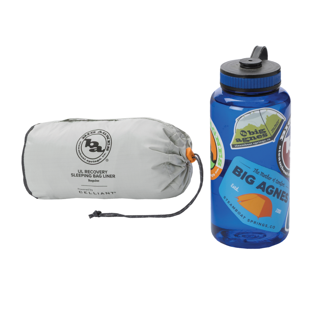 A compact gray Big Agnes UL Recovery Sleeping Bag Liner in a stuff sack sits beside a blue water bottle decorated with colorful stickers.