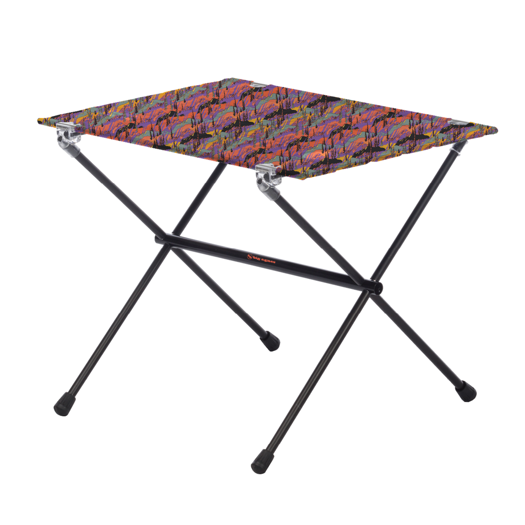 The Big Agnes Woodchuck Camp Table - Alpenglow is a lightweight, foldable outdoor table featuring black metal legs and a rectangular top with a colorful abstract design, shown on a plain white background.