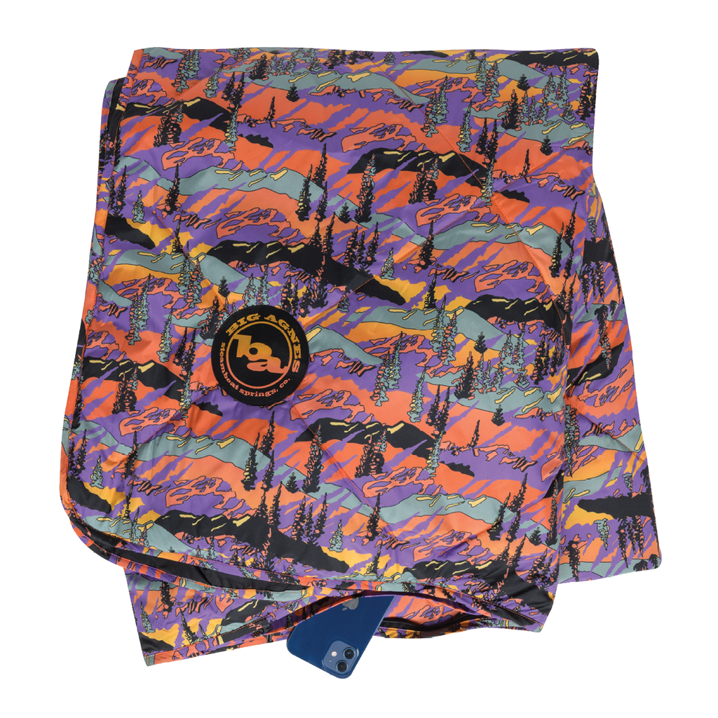 Colorful mountain-patterned towel with a brand logo on a white background