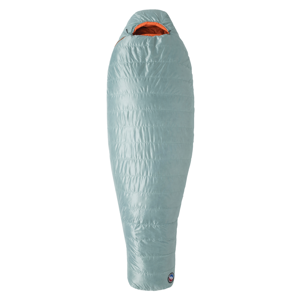 The Big Agnes Women's Greystone 30° mummy sleeping bag in light blue features an orange interior, tapered footbox, and hooded top for head coverage. It is displayed upright against a plain white background.